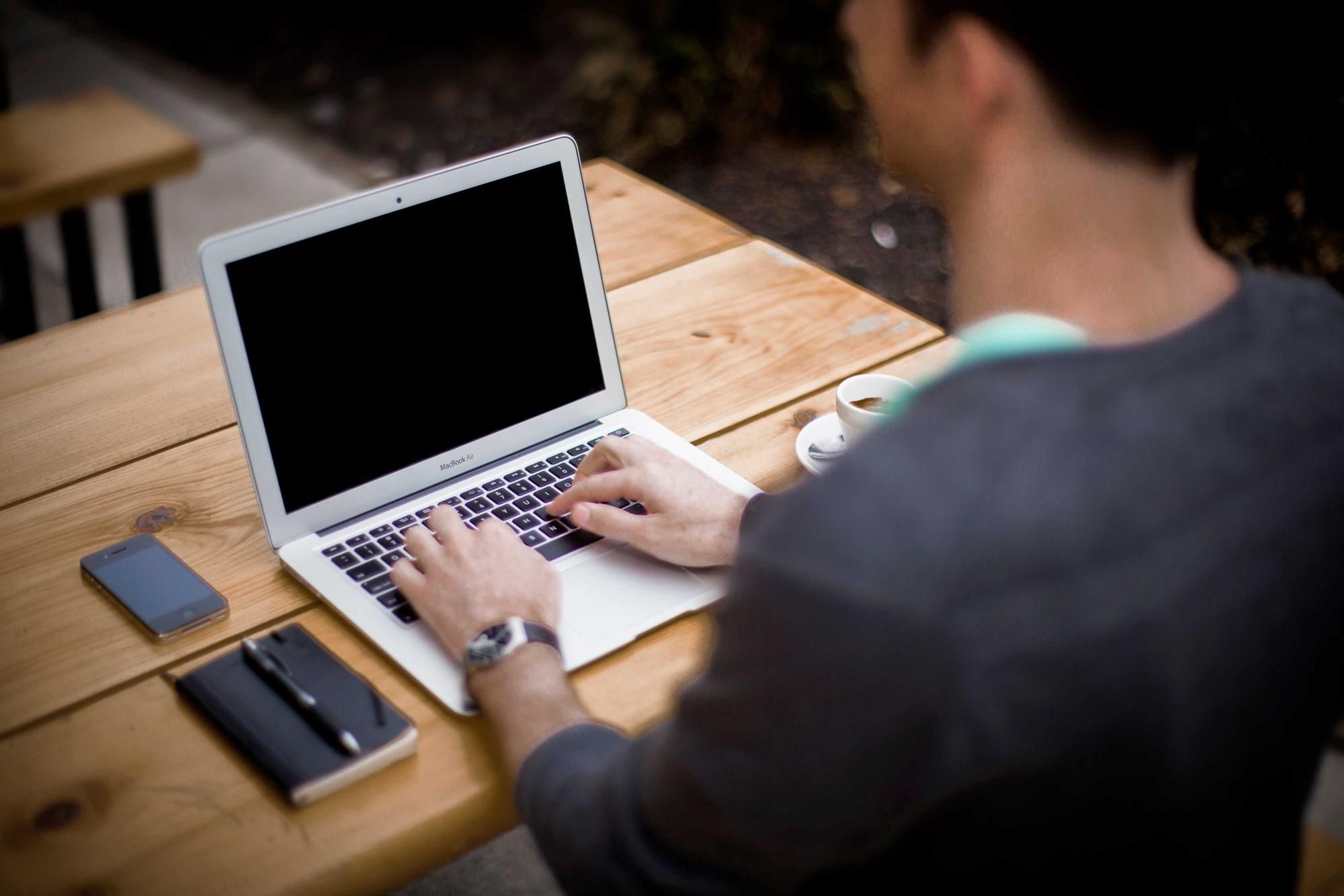 Developer typing on a laptop at a wooden table